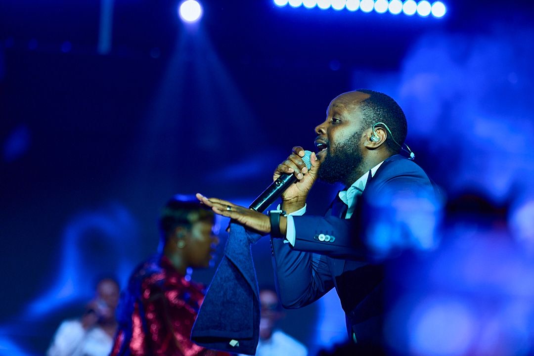 A performer under blue stage lights at a launch event, shot by Simply Art Creative